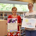 Zwei Frauen stehen vor Bücherregalen. 